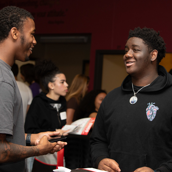 Two students talking while at an indoor event.